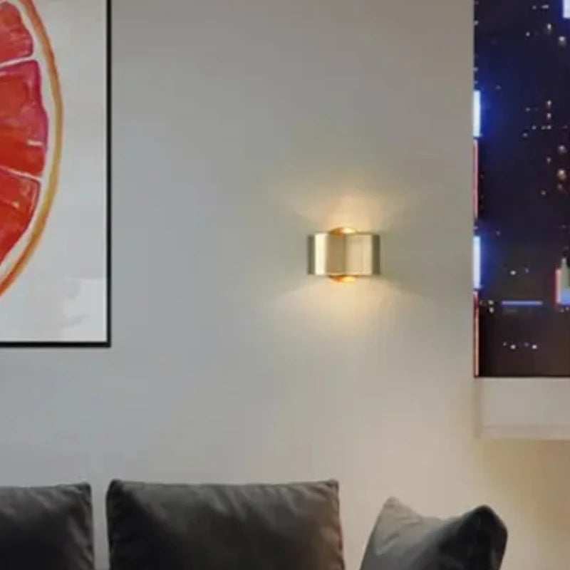 Gold wall sconce on a wall with framed artwork in a room setting