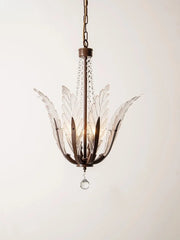 A close-up view of a bronze chandelier with clear glass leaf-shaped shades and a single hanging crystal.