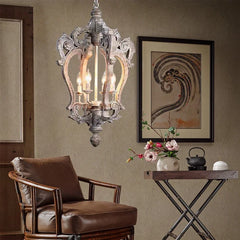 Decorative chandelier hanging above a brown armchair with a small table and floral arrangement in the foreground.