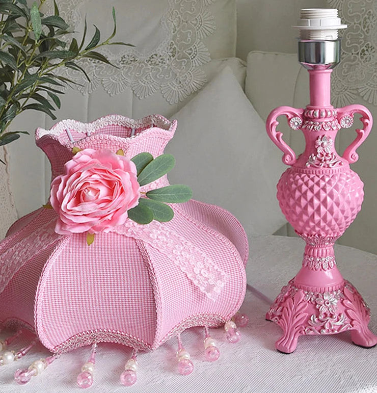 Pink decorative lamp with floral design on a white surface