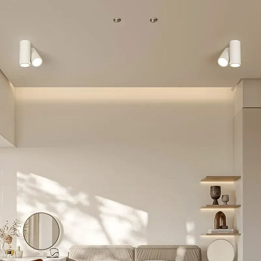 Close-up of two white cylinder spotlights on a ceiling, emitting warm light.