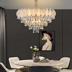 A glamorous tiered chandelier with cascading crystals and a polished chrome finish hangs above a dining table.