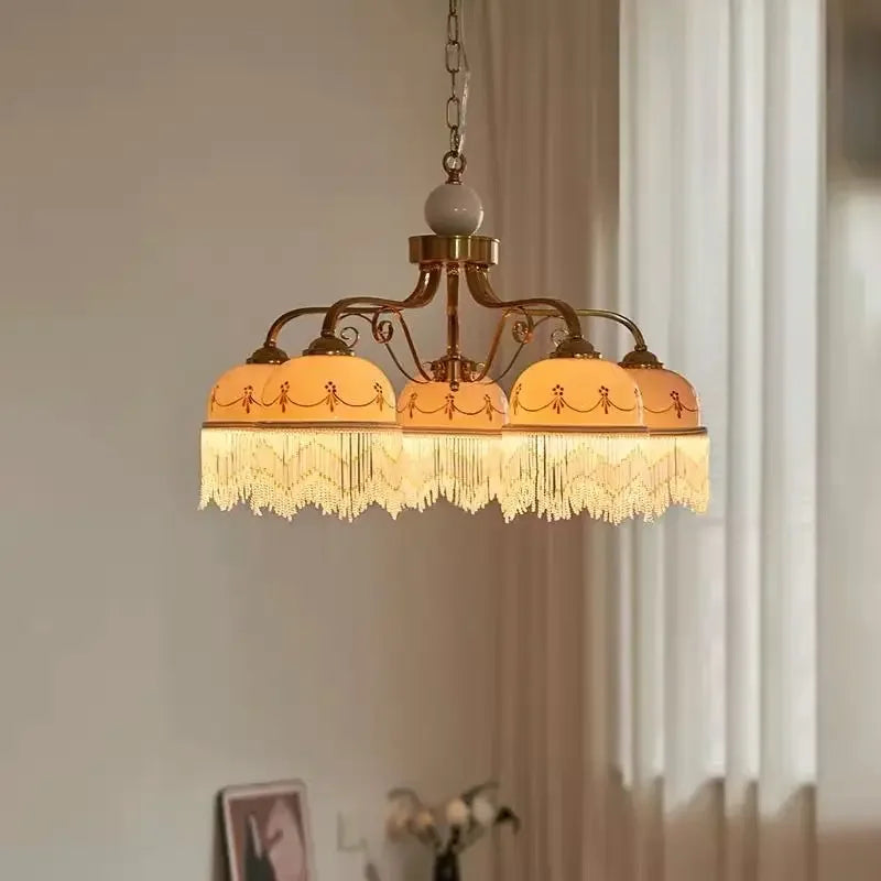Gold floral ceramic pendant light illuminated, casting a warm glow with white tassels.