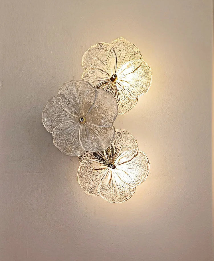 Decorative wall light fixture with floral design on a plain wall.