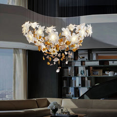 A chandelier shaped like a heart made of gold floral elements and clear crystals, suspended above a living room seating area.