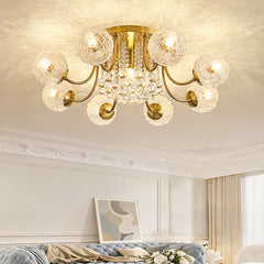 A polished gold semi-flush ceiling light with ripple glass globes and crystal accents, illuminating a living room with a blue sofa and artwork.
