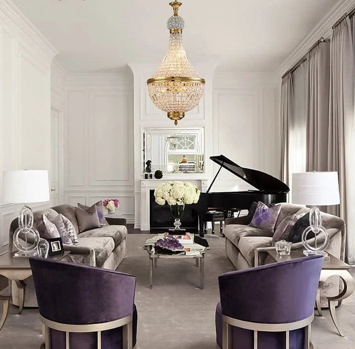 Luxurious living room with grand piano, chandelier, and purple chairs.