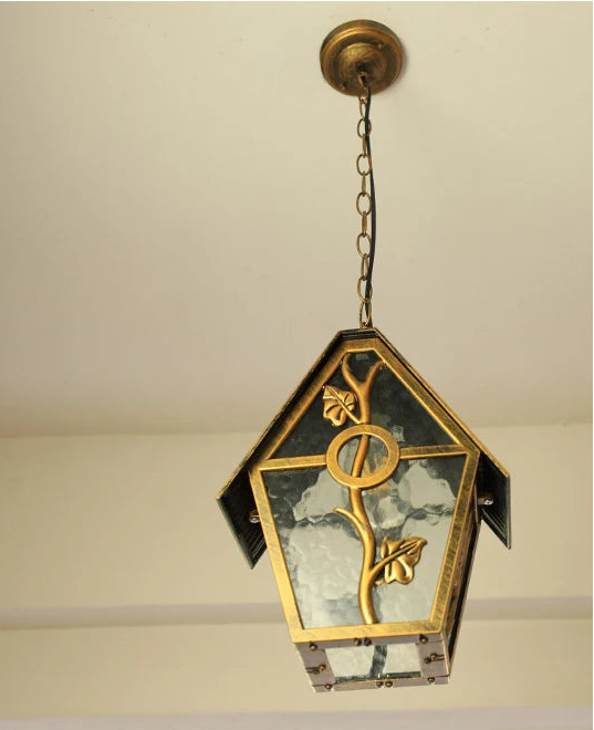 Decorative pendant light with gold accents and glass panels on a neutral background