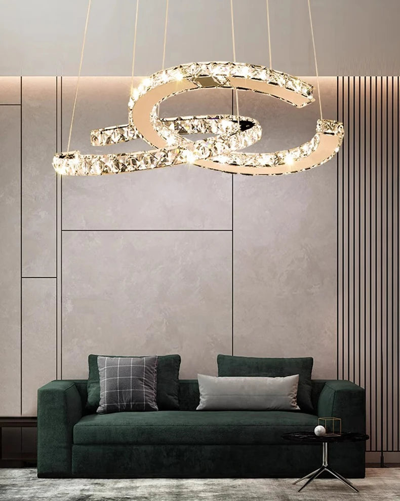 Modern living room with a green sofa, decorative pillows, and a stylish chandelier.