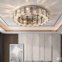 A bedroom with a modern interior, illuminated by a circular semi-flush ceiling light with a chrome frame and crystal embellishments.