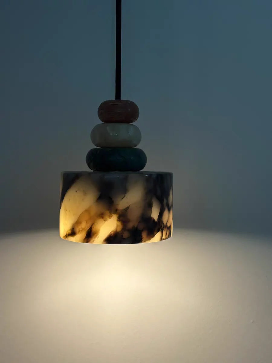Pendant light with marbled design and stacked stones on a gradient background