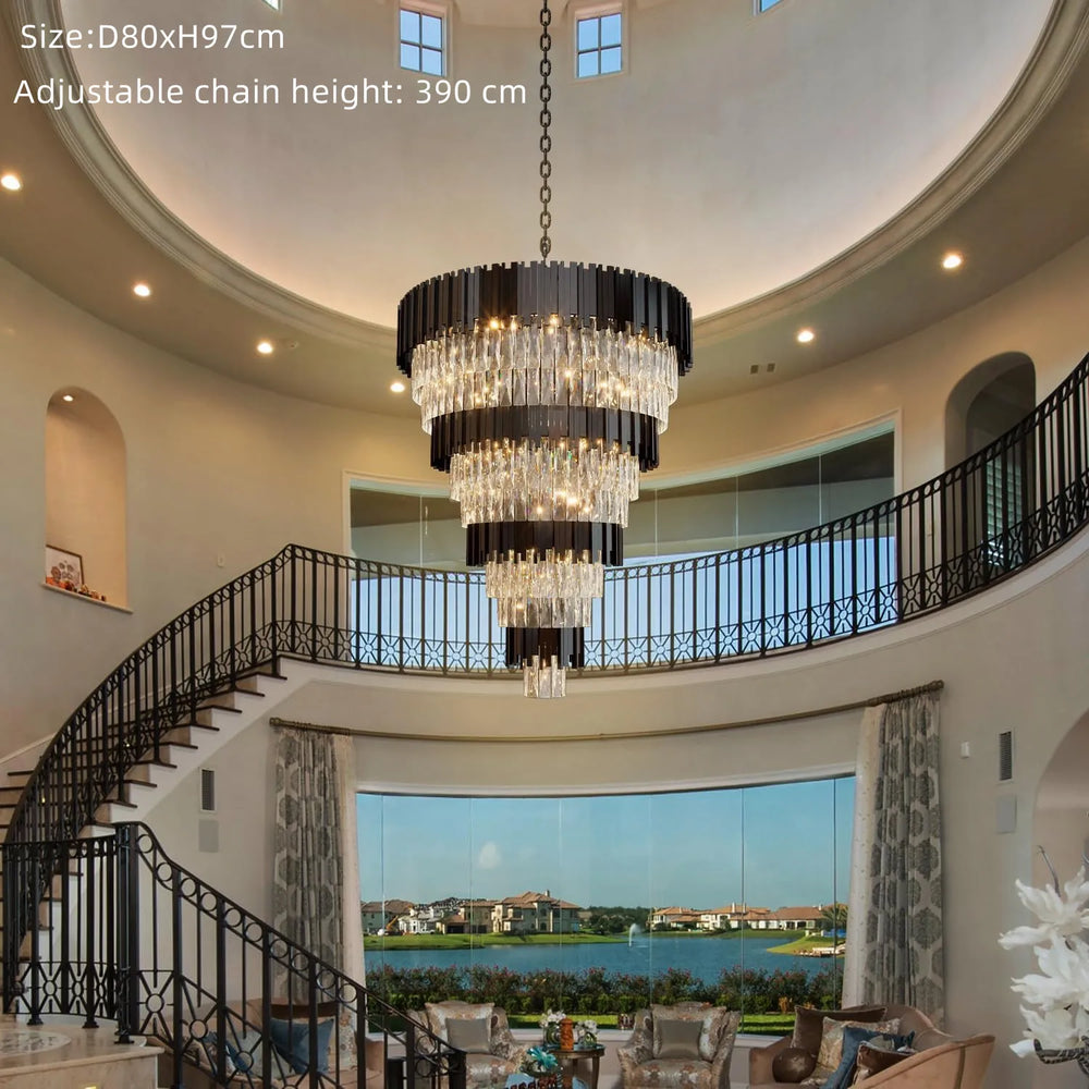 Luxurious chandelier hanging in a spacious room with a staircase and large windows.