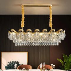 Gold cascading chandelier with teardrop crystals hanging above a dining table