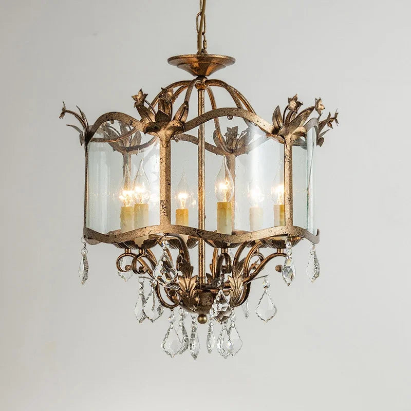 A gold chandelier with a vintage distressed finish and glass lampshades, featuring elegant crystal accents.