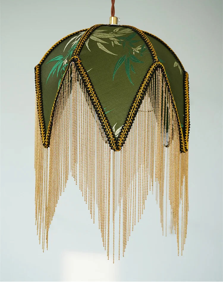 Decorative lamp with green floral design and gold fringe on a light gray background