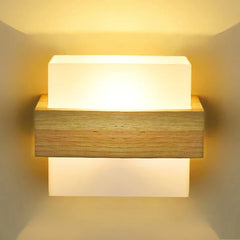 Front view of a wall-mounted light fixture with a central wooden element sandwiched between two frosted glass panels, casting a soft glow.