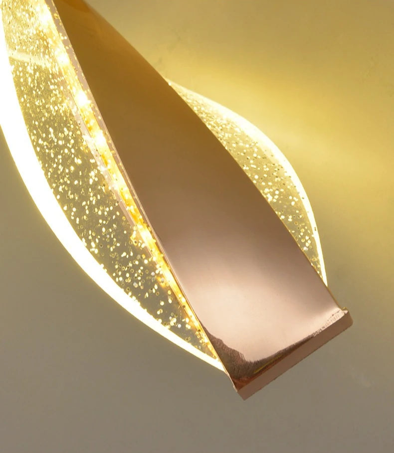 Modern wall light fixture with a gold finish on a neutral background