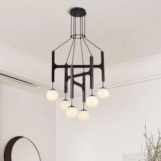 Close-up view of the dark wood and black metal frame of a multi-arm chandelier with white globe shades.
