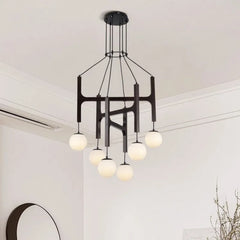 Close-up view of the dark wood and black metal frame of a multi-arm chandelier with white globe shades.