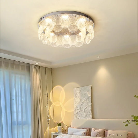 Ceiling light with chrome base and cascading textured glass discs, casting warm light on a bedroom ceiling