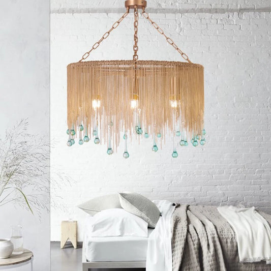 Gold chain tassel teardrop pendant light illuminating a modern bedroom with a brick wall