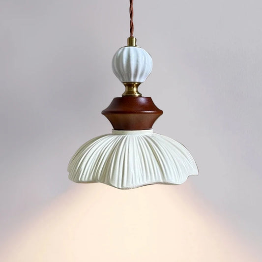 A resin and walnut pendant light with a bell-shaped, ribbed shade, illuminated from below, showcasing its warm light.