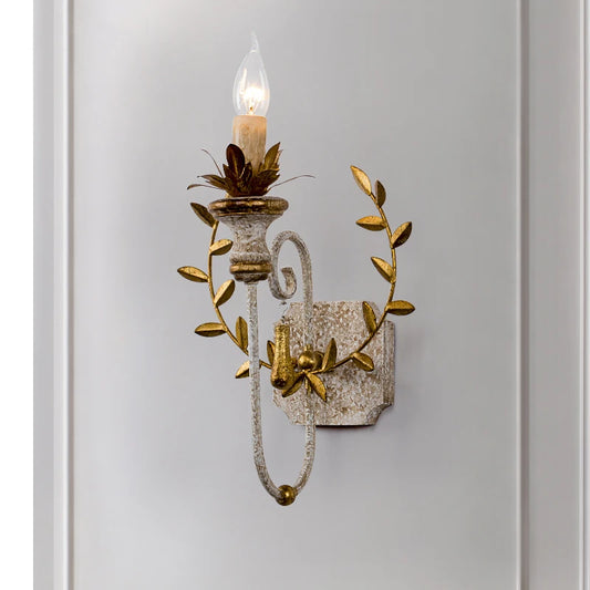 Close-up of a distressed gold floral leaf wall sconce showing intricate detailing and a candle-style light.