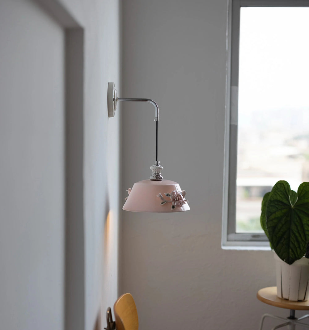 Pink wall-mounted lamp in a room with a window and plant