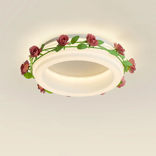 Close-up of a white semi-flush ceiling light featuring a ring design wrapped with a green vine and pink roses.
