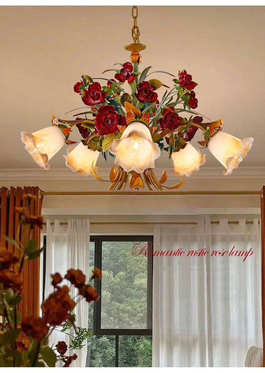 View of a gold floral chandelier with red rose buds, showcasing the intricate metalwork and frosted glass shades.