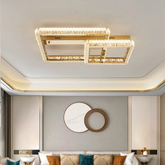 Gold geometric flush mount ceiling light with multiple rectangular frames adorned with clear crystals, installed in a bedroom above a bed.