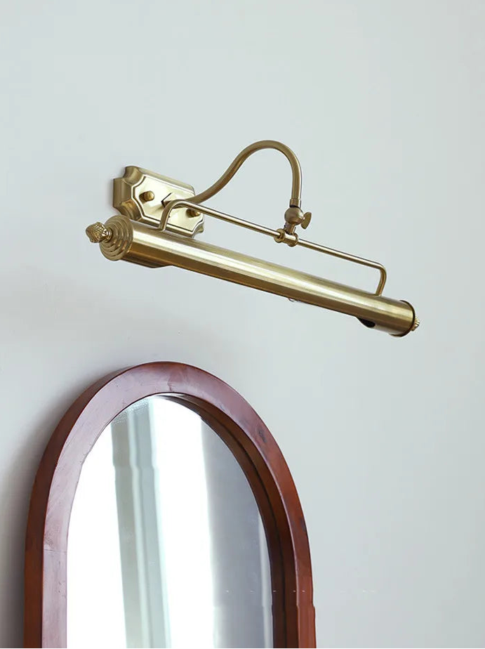 Brass wall-mounted lamp with a mirror on a light gray background