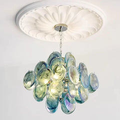 A blue and green glass disc chandelier hanging from a white ceiling.