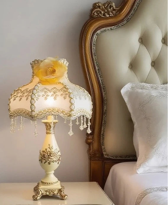 Decorative table lamp on a nightstand next to a bed with an ornate headboard.