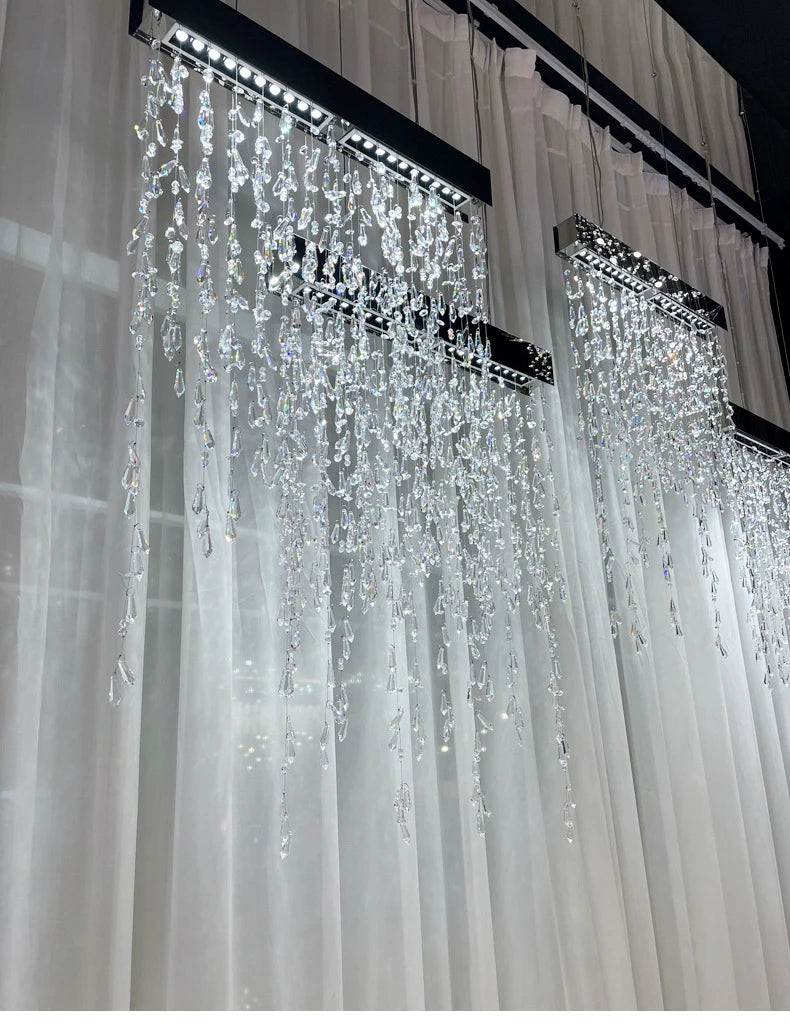 Crystal chandelier hanging from a ceiling with white curtains in the background