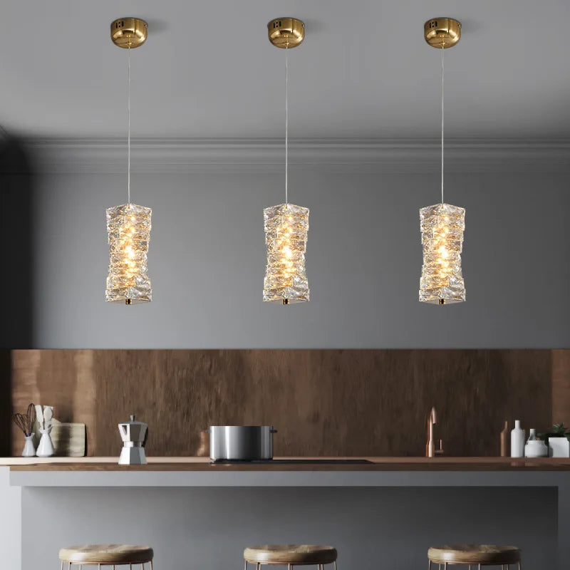 Three pendant lights hanging above a kitchen counter with a neutral color scheme.