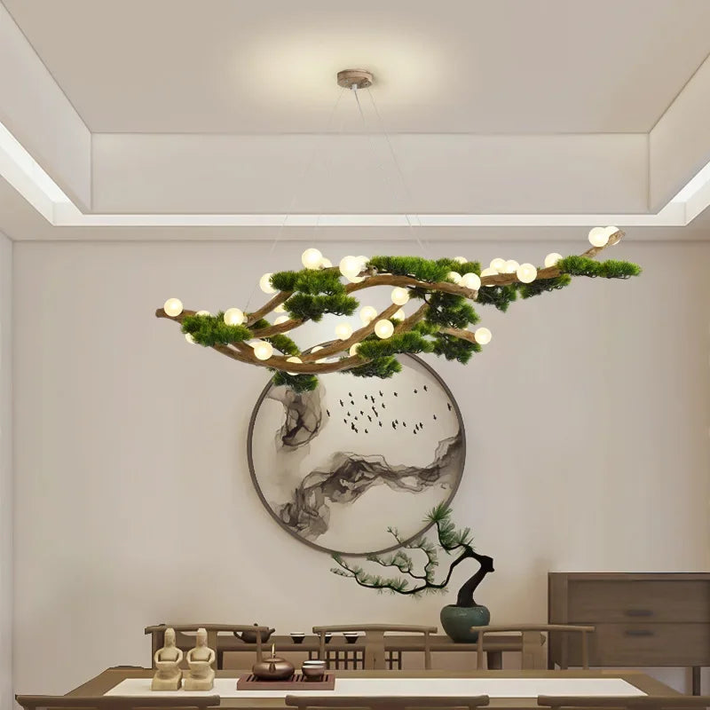 A branch-shaped chandelier with multiple small LED bulbs, resembling a natural tree branch adorned with green foliage, suspended from the ceiling in a modern dining room.
