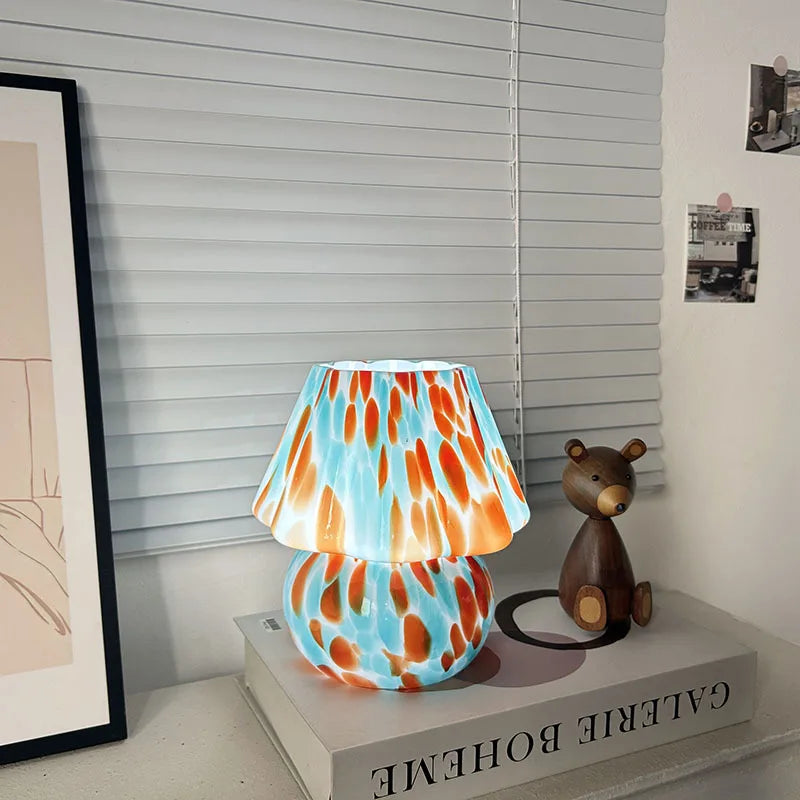 Colorful lamp with a pattern on a shelf next to a small bear figurine.