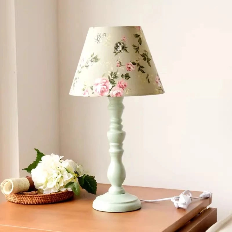Floral-patterned lampshade on a light green base on a wooden surface.