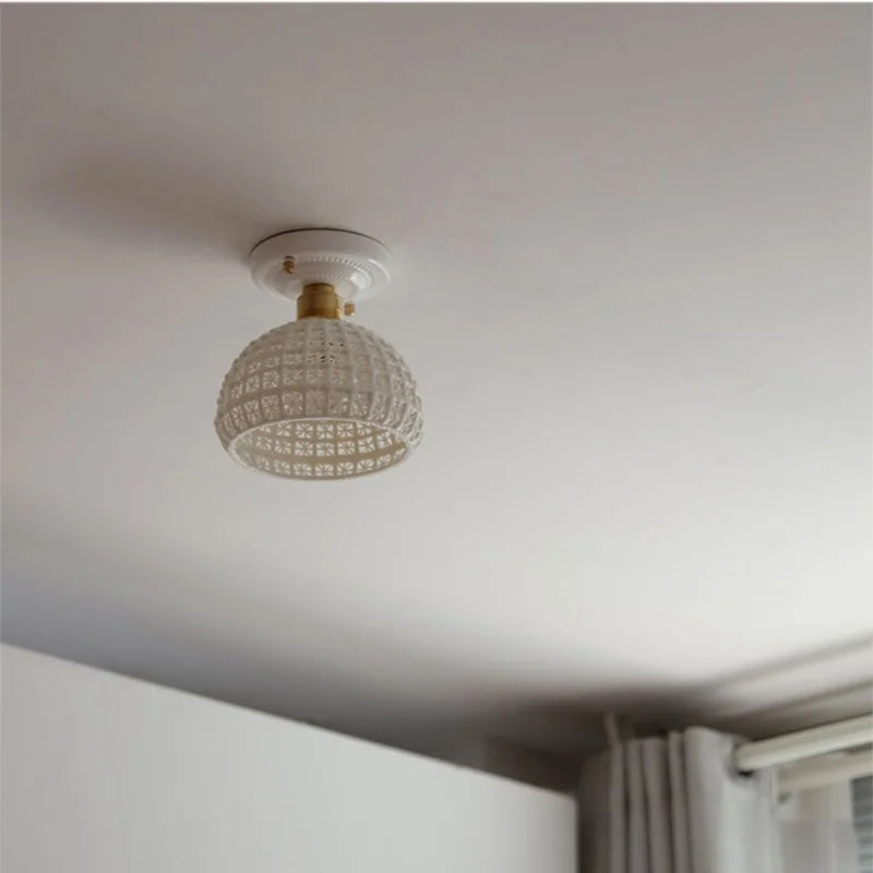 Ceiling light fixture with decorative glass shade on a white ceiling