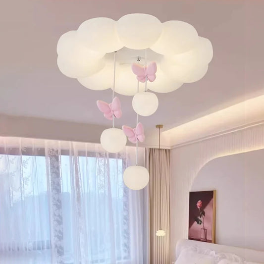 Close-up of a white cloud-shaped ceiling light with pink butterflies and hanging orbs in a bedroom setting.