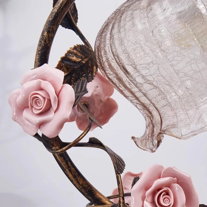 Decorative lamp with pink roses and a cracked glass shade on a light gray background