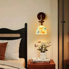 Bedroom setting featuring a wood and glass shell wall sconce above a nightstand with a vase of flowers.