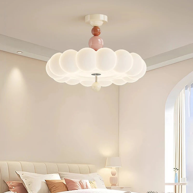 A bedroom scene with a pink cloud flush mount ceiling light casting a soft glow over a bed.