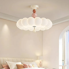 A bedroom scene with a pink cloud flush mount ceiling light casting a soft glow over a bed.