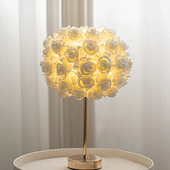 Close-up of the white rose bud floral shade of a gold table lamp.