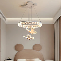 A close-up of a crystal ring pendant light with butterfly accents, hanging in a softly lit bedroom.