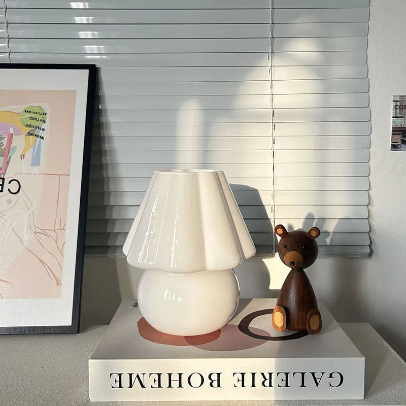 White lamp and brown bear figurine on a 'Galerie Boheme' box with blinds in the background