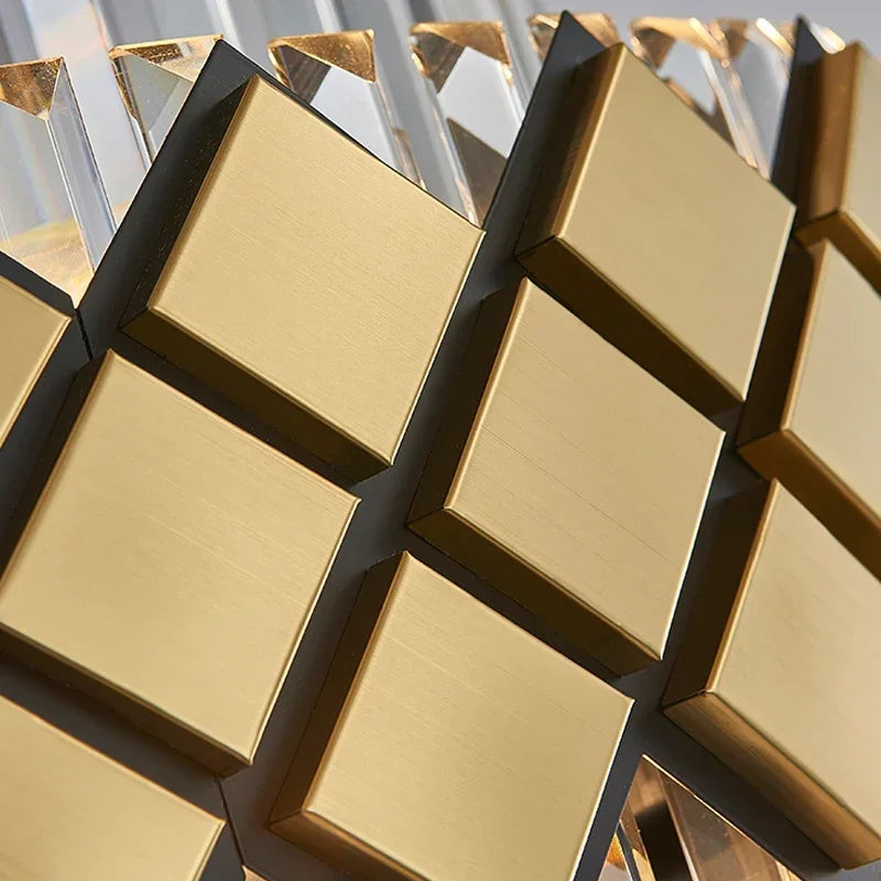 Detailed view of the brushed gold square accents and clear faceted crystal prisms on a tiered chandelier.