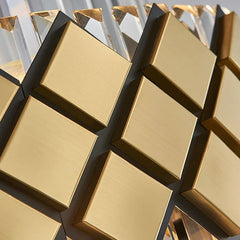 Detailed view of the brushed gold square accents and clear faceted crystal prisms on a tiered chandelier.